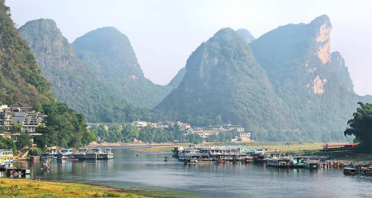 Un río lleno de barcos contra un telón de fondo de paisaje montañoso.