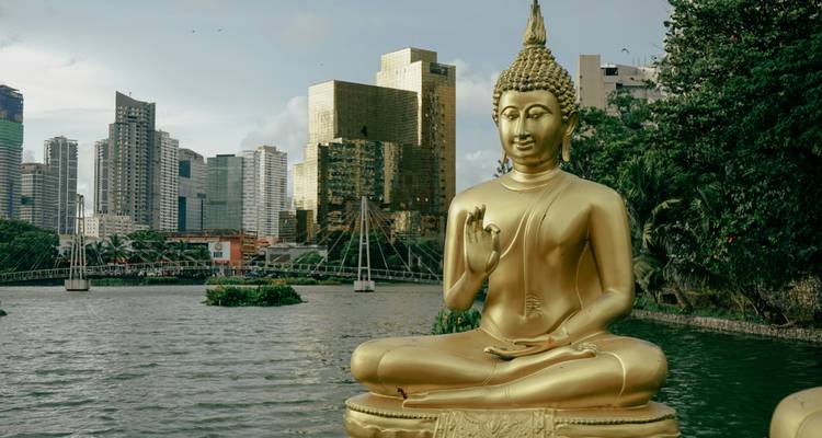 Estatua de Buda dorada sentada junto al Lago Beira con el skyline de Colombo de fondo
