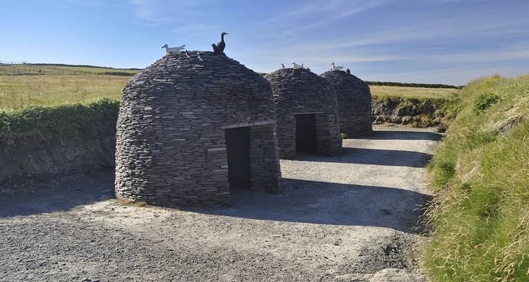 Trois structures en pierre en forme de ruche dans un champ.