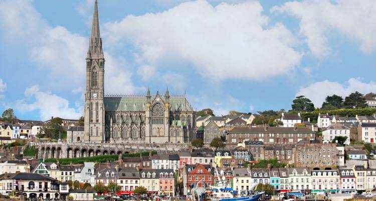 Paysage urbain avec une église proéminente surplombant des bâtiments colorés.