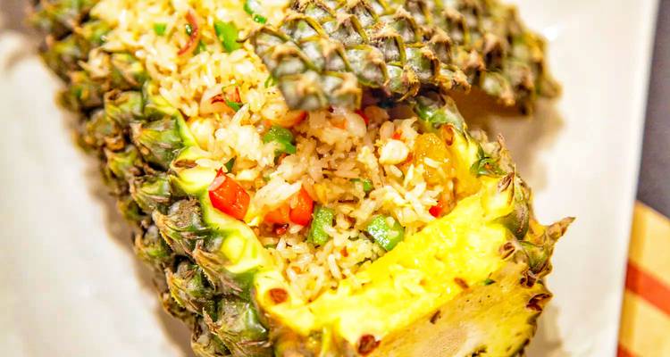 Ananas gevuld met gebakken rijst, gegarneerd met groenten.