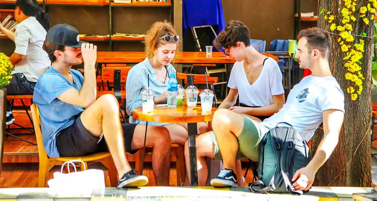 Groep vrienden die aan een tafel buiten zitten.