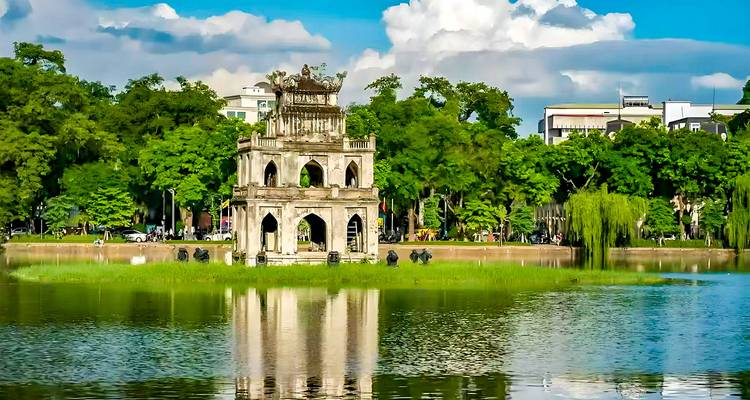 Historisch gebouw naast een meer omringd door bomen.