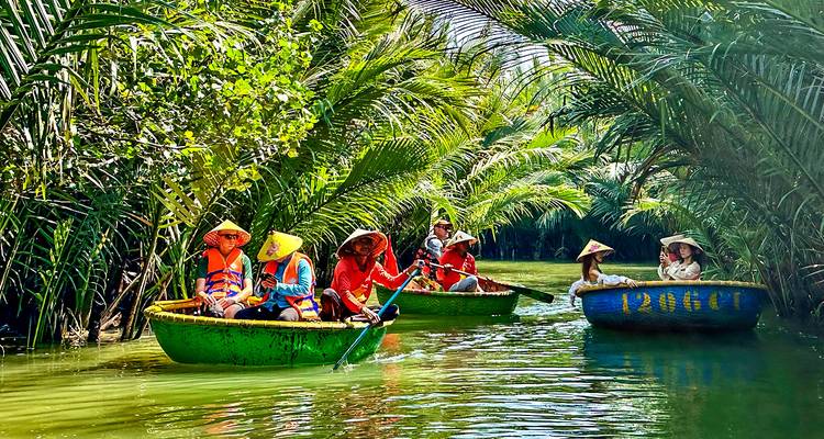 Eine Gruppe von Menschen, die in traditionellen runden Booten fahren, umgeben von üppigem Grün.