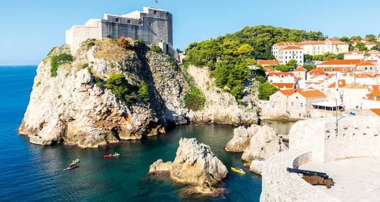 Fort Lovrijenac perché sur une falaise côtière spectaculaire surplombant une eau émeraude où des kayaks colorés naviguent en contrebas.