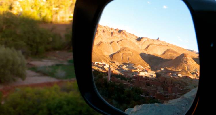 Felsige Landschaft, die sich in einem Autospiegel spiegelt, wobei die gespiegelte Ansicht leicht verschwommen ist.