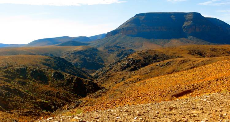 Weite Wüstenlandschaft mit einem markanten Felsmesa unter klarem Himmel.