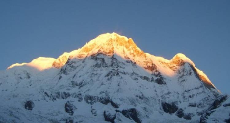 Sonnenaufgang auf einem schneebedeckten Berggipfel.