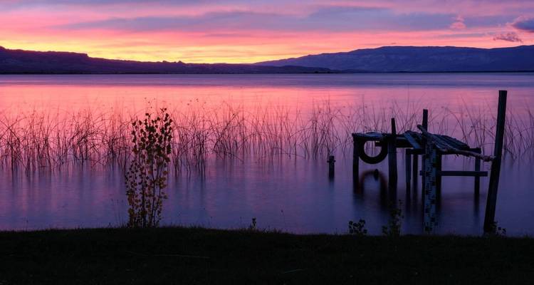 Meer bij zonsondergang met het silhouet van een oude steiger.