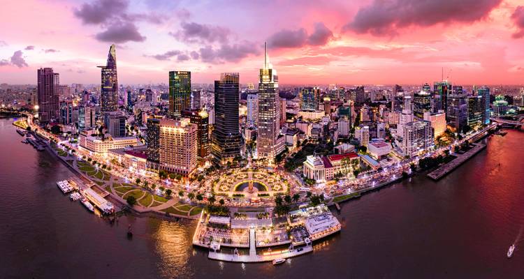 Dazzling aerial panorama of Ho Chi Minh City skyline illuminated at sunset along the Saigon River.