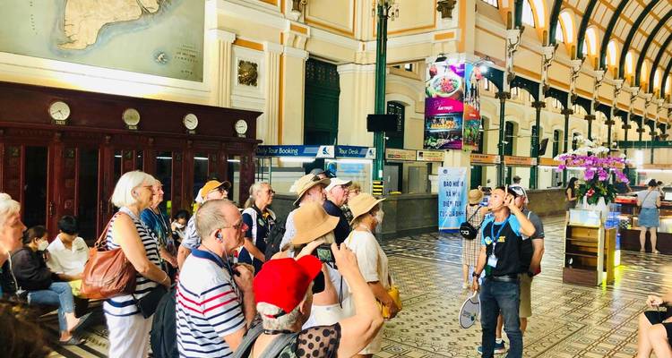 Tour guide addressing a group of travelers inside a grand colonial post office hall.
