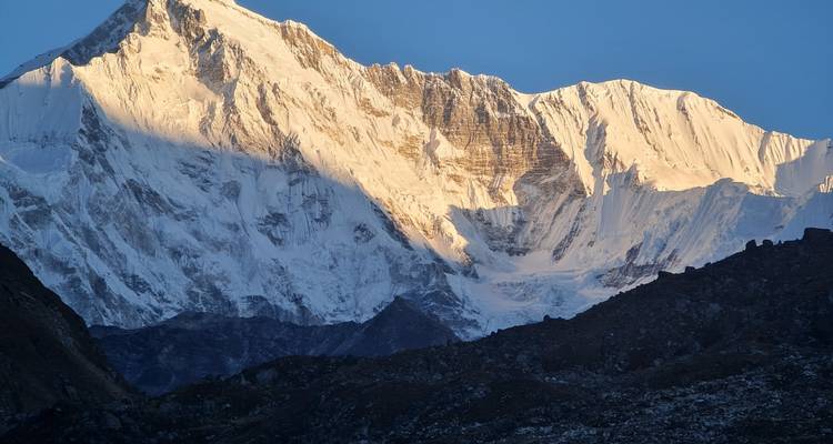 Pico nevado bañado en cálida luz dorada con una sombra profunda proyectada en su cara.