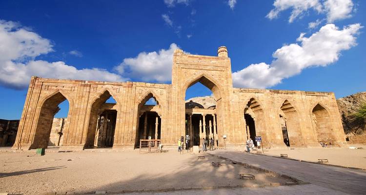 Ruinen einer alten Steinstruktur mit Menschen, die sie betrachten.
