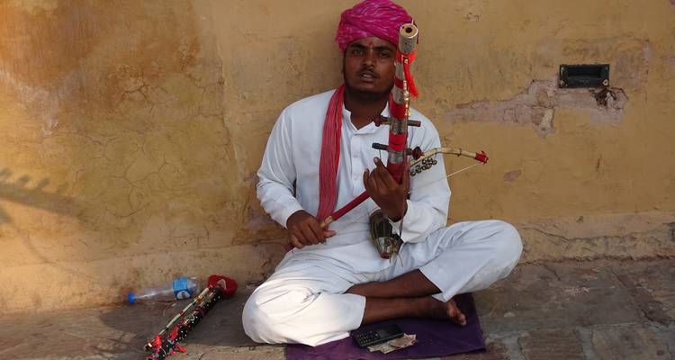 Un músico con vestimenta tradicional tocando un instrumento de cuerda.
