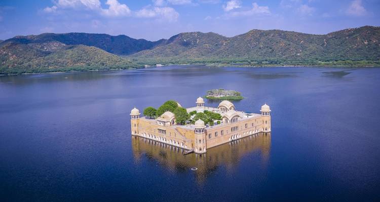 Jal Mahal rodeado por un lago y paisaje montañoso.