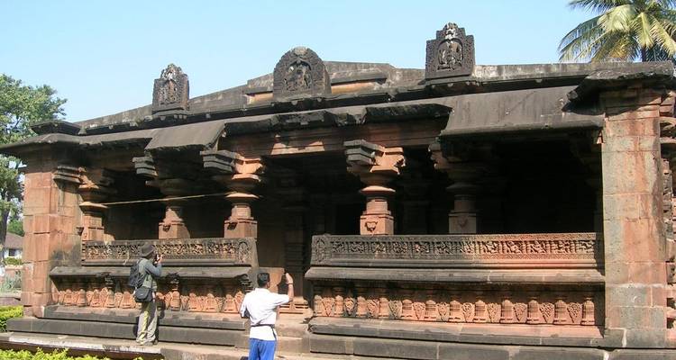 Ein historischer Tempel mit Steinmetzarbeiten und Touristen, die ihn erkunden.