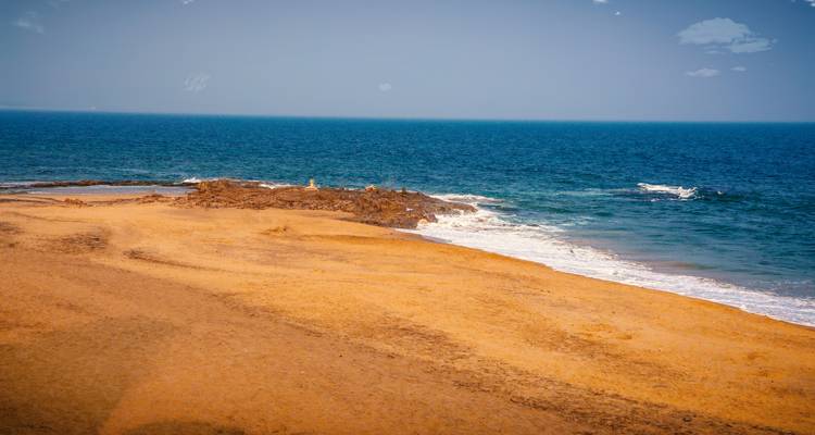 Sandy beach with waves hitting the shore.