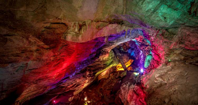 Colorfully lit interior of a cave with stalactites.