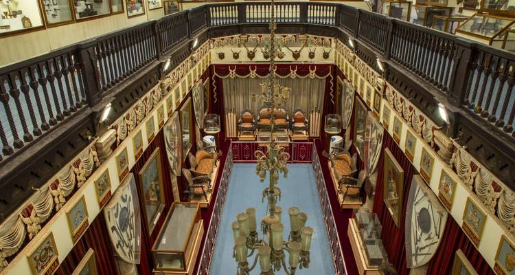Interieur van een historisch gebouw met kroonluchters en zitplaatsen