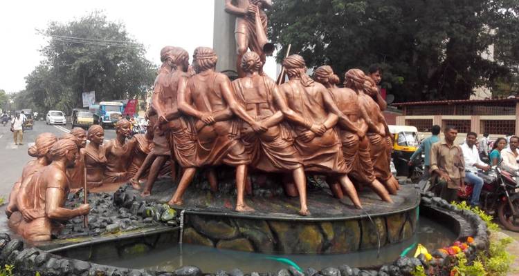 Bronzestatue einer Personengruppe auf einem öffentlichen Platz mit Schaulustigen.