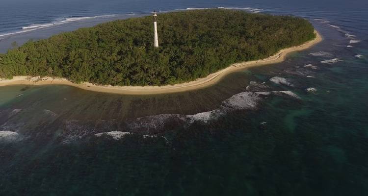 Island with a lighthouse surrounded by water.