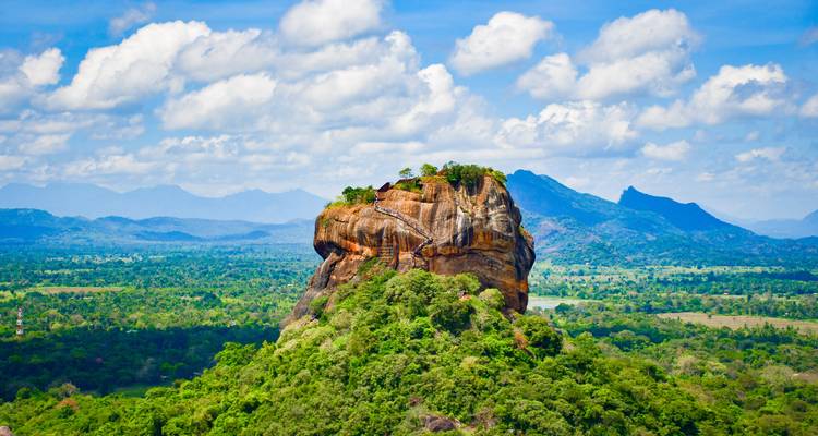 Le dramatique Rocher du Lion de Sigiriya s'élevant au-dessus de la jungle verdoyante avec des montagnes au loin.
