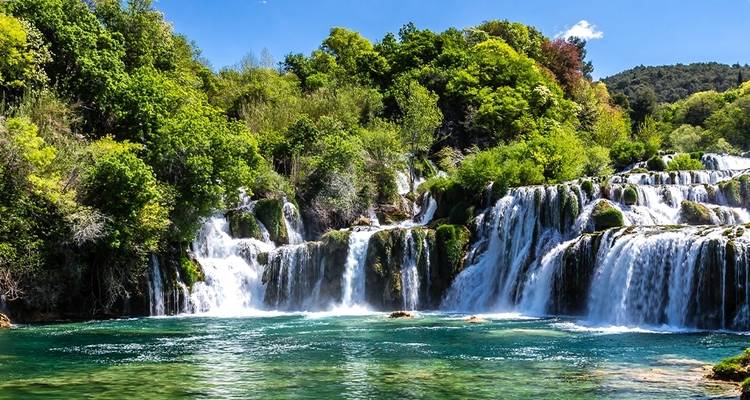A lush waterfall flowing into a turquoise pool.