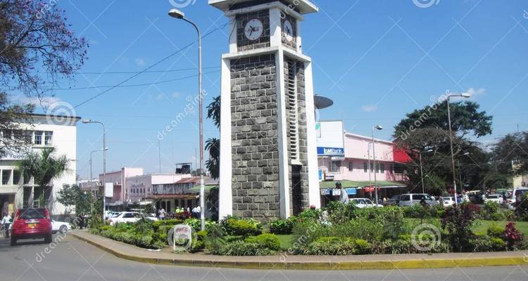 Stone tower with clock and surrounding buildings in a cityscape.