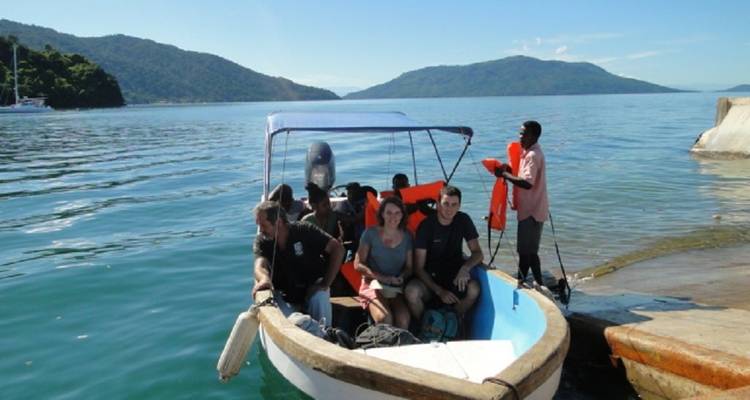 Group of people on a boat in a scenic lake setting.