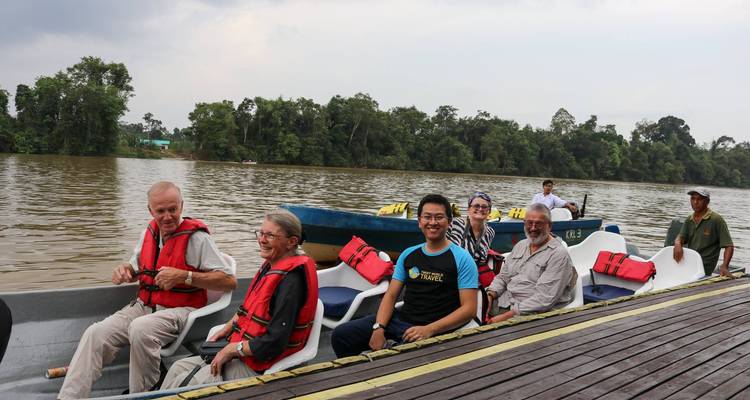 Tourists on a boat enjoying a river cruise with forested banks.