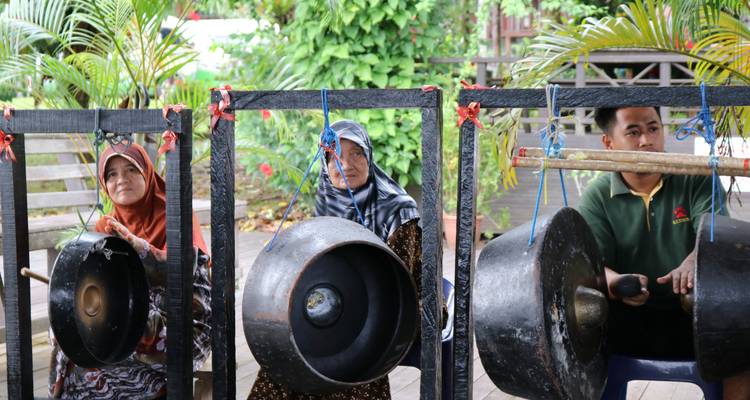 Local villagers playing large gongs as part of a traditional musical performance.