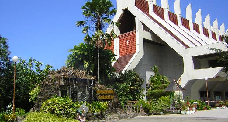 Edificio moderno con palmeras y una pequeña cascada.