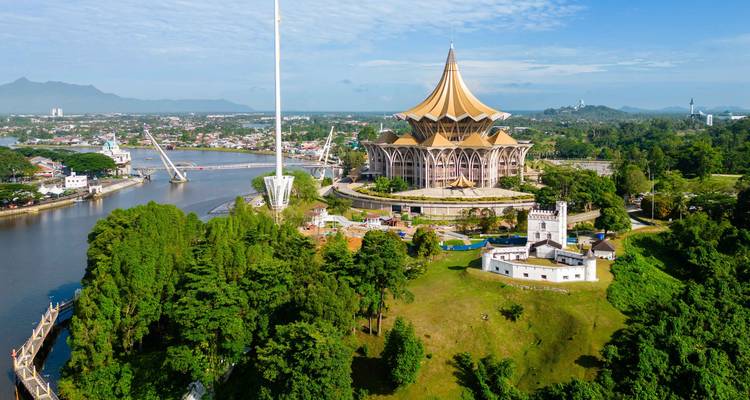 Vista aérea de la Asamblea Legislativa del Estado de Sarawak con techo dorado en Kuching, junto al amplio río Sarawak.