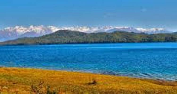 Farbenfrohe Landschaft mit einem See und fernen Bergen.