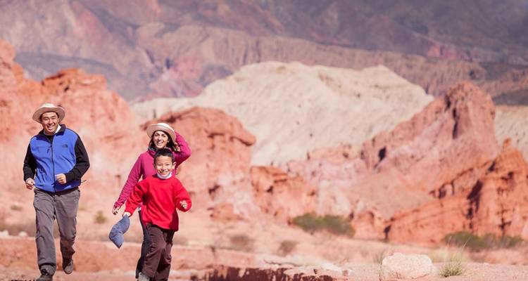 Familie rennend in een rotsachtig woestijnlandschap.