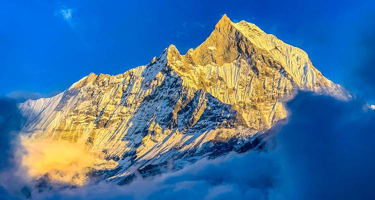 Eine dramatische schneebedeckte Bergspitze, die von der Sonne beleuchtet wird.