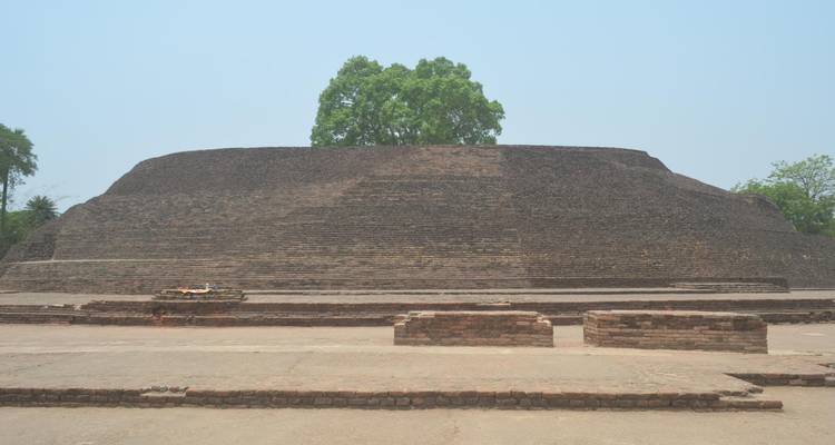 Ruines massives d'un ancien stupa en brique avec de larges marches sous un ciel brumeux