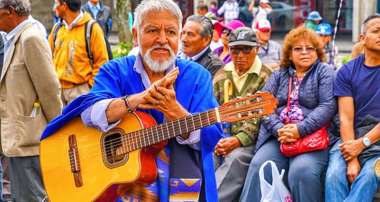 Älterer Mann spielt Gitarre auf der Straße, während Leute zuschauen.