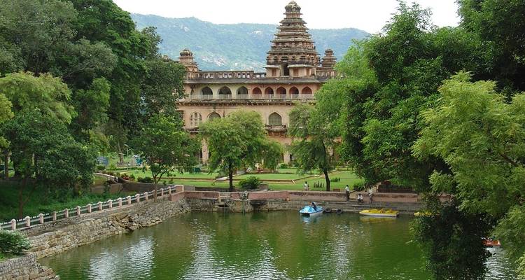 Traditionelles Gebäude an einem Teich mit Bergkulisse.