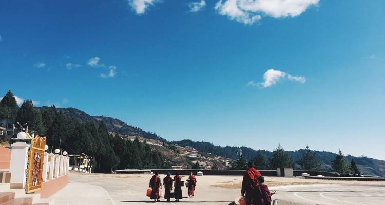 Monniken die wandelen langs een bergachtig landschap onder een heldere hemel.