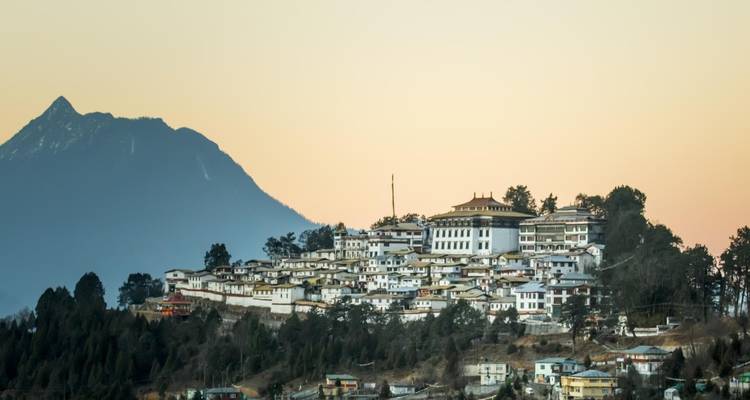 Nederzetting op een heuvel met een groot gebouw, berg op de achtergrond.