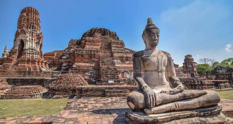 Ruines anciennes avec une statue de Bouddha assis proéminente.