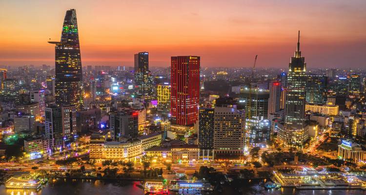 La ligne d'horizon de la Ville de Ho Chi Minh brille de lumières colorées au crépuscule se reflétant dans le fleuve Saigon.