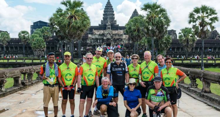 Groupe de cyclotourisme posant devant le complexe de temples emblématique d'Angkor Wat.