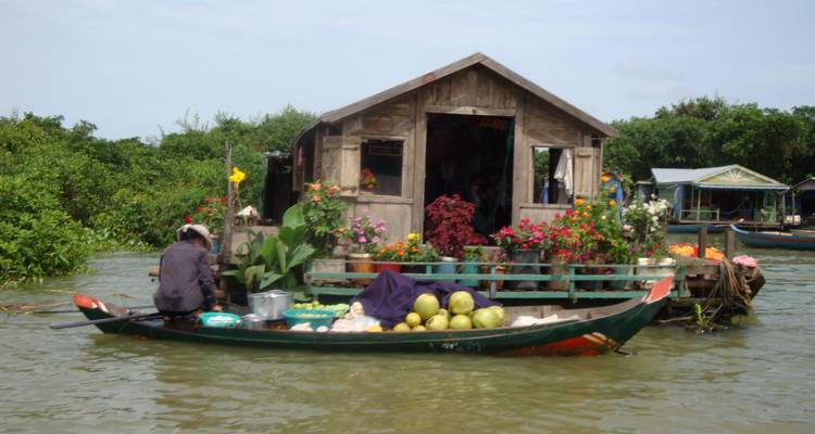 Hombre en un barco decorado con flores en un río.