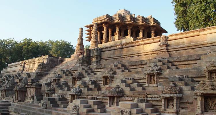 Zijaanzicht van een tempel met gedetailleerd steenwerk, trappen en bomen.