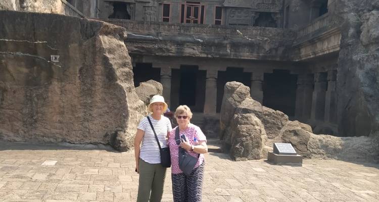 Twee vrouwen die staan bij oude in rots uitgehouwen architectuur.