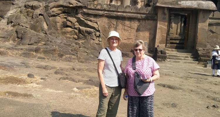 Twee vrouwen poseren voor oude in rots uitgehouwen architectuur.