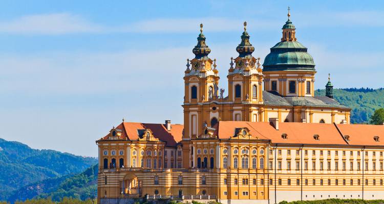 L'Abbaye baroque de Melk perchée au-dessus de collines boisées sous un ciel bleu dégagé.