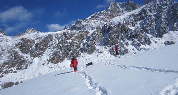 Wandelaars die door een besneeuwde berglandschap trekken.